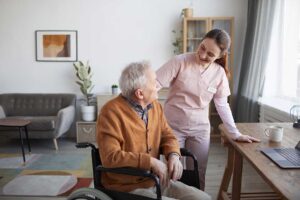 Caregiver speaks respectfully with an older resident in a bright assisted living common room.